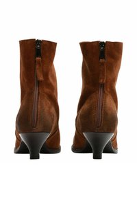 Stivaletti in suede marrone con tacco conico di media altezza, dotati di chiusura con cerniera posteriore e un design leggermente slouch.