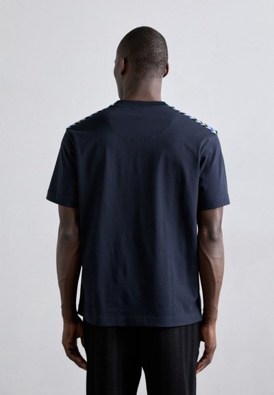 T-shirt en coton bleu marine avec des accents multicolores aux épaules, manches courtes et encolure ronde. Texture lisse, coupe décontractée.