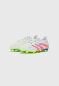 Botas de fútbol blancas con acentos en rosa y verde neón, con una parte superior texturizada, cierre de cordones y tacos multicolores para tracción.