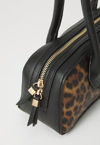 Black handbag with a leopard print side panel, featuring gold zipper closure and accents, structured shape, and dual handle design.