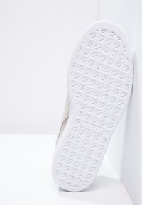 Weiße Sneaker-Sohle mit einer strukturierten Oberfläche und rautenförmigen Mustern sowie einem subtilen, hellgrauen Obermaterial.