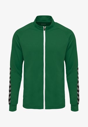 Green zip-up jacket made of textured fabric, featuring white zipper, solid green body, and black and grey chevron pattern on sleeves.
