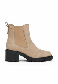 Bottine en suede beige avec un gros talon et une semelle noire, panneau latéral élastique et languette à l'arrière, arborant un petit logo doré près du haut.