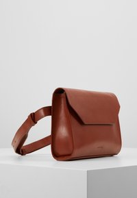 Borsa a spalla in pelle marrone con design piatto, chiusura a patta e tracolla regolabile. Texture liscia senza motivi visibili o hardware.