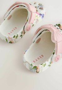 Lille lillede taimekirjaga valged kummist klotsid roosa aktsendiga ja tagahihnaga. Tekstureeritud sisemus, kus on roosaga trükitud "BAKER".