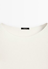 Jasno beżowy sweter z szerokim dekoltem, z czarną metką z napisem "Massimo Dutti" z tyłu. Prosty, minimalistyczny design.