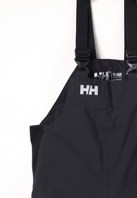 Schwarze wasserdichte Latzhosen mit verstellbaren Trägern, ausgestattet mit einem auffälligen Logo und strukturiertem Stoff, entworfen für Langlebigkeit und Komfort.