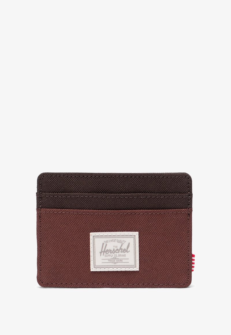Brązowy portfel na karty z wieloma przegródkami, z białą łatą z logo i czerwono-białym paskiem po boku. Gładka tekstura.