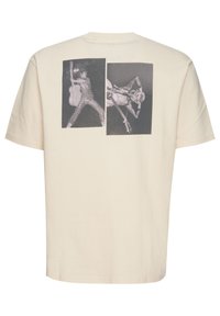 Crème katoenen t-shirt met twee zwart-witfotoafdrukken op de achterkant. Korte mouwen, ronde hals en relaxte pasvorm.