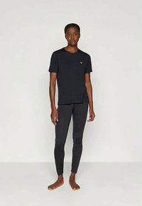 Černé přiléhavé tričko s kulatým výstřihem a malým logem; spárováno s odpovídajícími černými legínami. Hladká textura, minimalistický design.