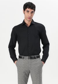 Black long-sleeve button-up shirt with a collar, paired with patterned grey and black trousers and a black belt. Smooth fabric texture.