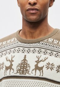 Πλεκτό πουλόβερ με εκρού βάση και καφέ γεωμετρικά σχέδια, σχέδια με τάρανδους και ριμπ λαιμόκοψη. Απαλή υφή, καθημερινό σχέδιο.