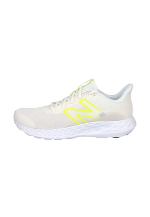 Zapatilla de running beige clara con suela acolchada blanca y logotipo "N" amarillo neón en el lateral, diseñada para uso atlético.