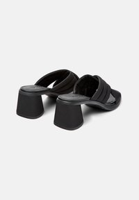 Sandales noires à talons avec une semelle texturée, dotées de larges brides et d'un talon bloc épais, fabriquées en matériau synthétique lisse.