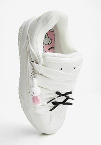 White sneaker with a textured upper, black ribbon accents, and a pink and white bunny keychain. Interior features a pink insole with bunny patterns.