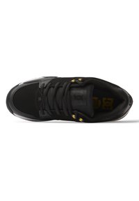 Sort sneaker med en tekstureret overdel, glatte detaljer, rund tå og sorte snørebånd. Har et logo på tungen og kontrasterende gule øskner.