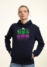 Felpa blu navy realizzata in morbido tessuto, con un design grafico che presenta personaggi creeper verdi su uno sfondo a griglia rosa. Tasca a marsupio frontale.