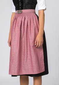 Traditioneller Dirndlrock in Pink mit einem strukturierten Muster. Hat einen gerafften Taillenbund und einen dekorativen Gürtel mit einer silberfarbenen Schnalle. Schwarzer Unterrock sichtbar.