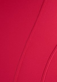 Roter Badeanzugstoff mit glatter Oberfläche, der kontrastierende Nähte und ein körpernahes Design aufweist, das eine stromlinienförmige Silhouette betont.