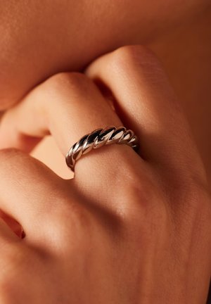 Silver twisted band ring featuring a smooth, reflective texture with alternating polished and matte sections. The design is circular and flexible.