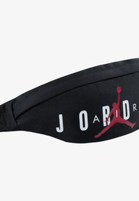 Saco de cintura preto em tecido com o atrevido texto branco "J O R D A N" e o logótipo vermelho Jumpman. Superfície texturizada com alça ajustável para conforto.