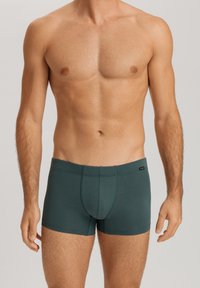 Boxer shorts de algodón verde con un ajuste ceñido, que cuentan con una costura horizontal para brindar estructura y una pequeña etiqueta de marca en la cinturilla.