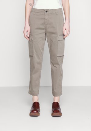 Cargo broek in licht taupe stof met een taps toelopende fit, voorzien van twee zijzakken en een knoopsluiting. Draag ze met donkerbruine klompen.