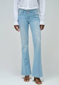 Vaqueros acampanados de color azul claro, fabricados en denim, con una cintura alta, diseño clásico de 5 bolsillos y un ligero desvanecimiento en los muslos.