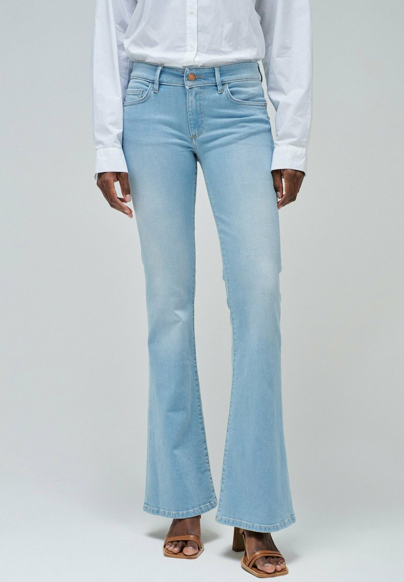 Vaqueros acampanados de color azul claro, fabricados en denim, con una cintura alta, diseño clásico de 5 bolsillos y un ligero desvanecimiento en los muslos.