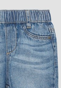 Pantaloni corti di denim blu con cintura elastica, caratterizzati da una tasca frontale e dettagli di cucitura in vista. Il tessuto ha una texture leggermente sbiadita.
