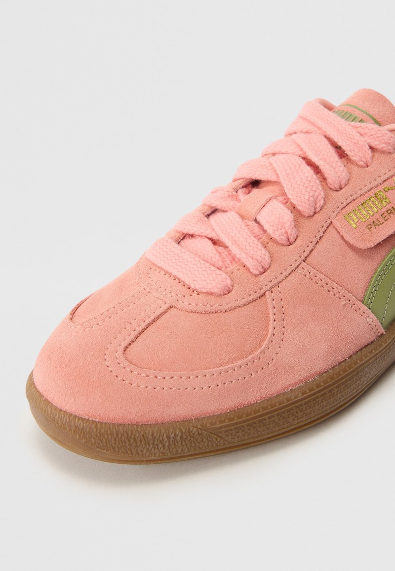 Baskets en daim rose avec semelle en gomme texturée, dotées d'accents verts et de lacets plats. Coutures détaillées et logo sur le côté.