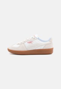 Zapatillas Puma Palermo en cuero crema y blanco con suela de goma. Las características incluyen cierre de cordones y acentos laterales texturizados.