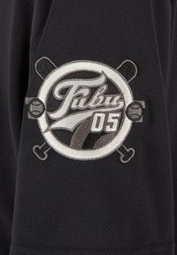 Tricou sportiv negru cu un logo circular brodat, având inscripția "Tubru 05," crose de baseball încrucişate și mingi de baseball. Material texturat cu detalii din plasă.