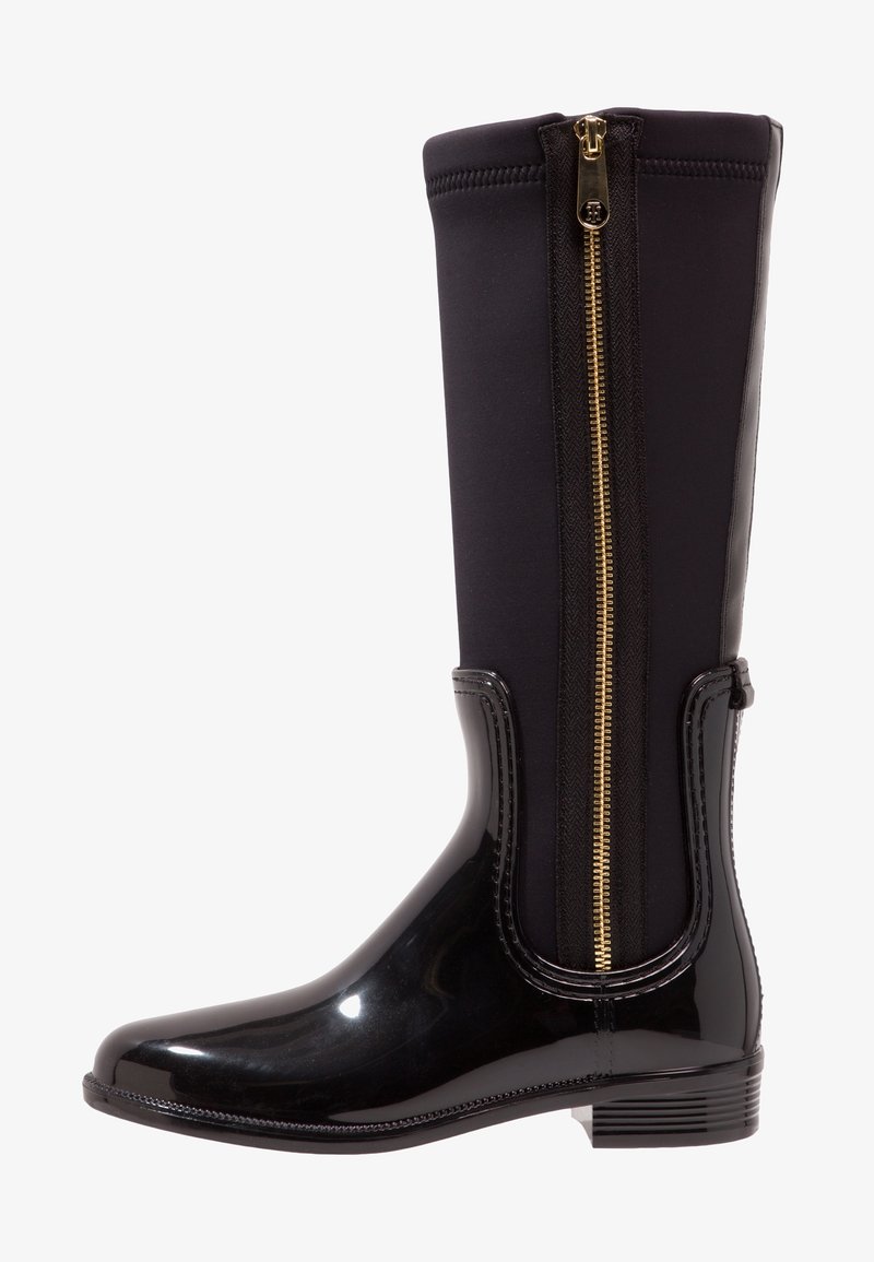 Botte de pluie noire montante jusqu'au genou avec finition brillante, fermeture éclair latérale dorée et semelle texturée, inclinée vers la gauche sur fond blanc.