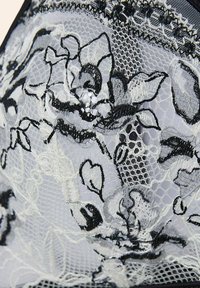 Black and white floral lace with intricate patterns, semi-transparent texture, featuring delicate stitching and scalloped edges.