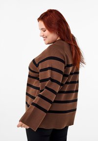 Maglione marrone con strisce nere, texture morbida, vestibilità ampia, maniche larghe e orlo a costine. La vista laterale mostra i dettagli delle spalle e del collo.