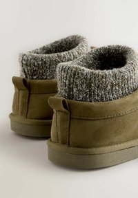 Olivengrøn nubuck ankelstøvler med en strikket grå manchet, der har en rund tå og flad sål. Manchetten er tekstureret og designet til varme.