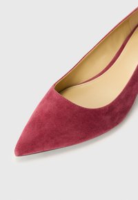Suedes pumps med spiss tå i dyp burgunder med en glatt innside og minimalistisk design, med en forsiktig buet topplinje og en flat såle.