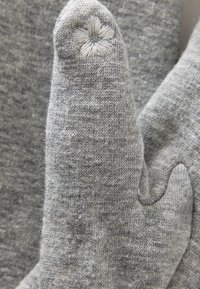 Guanti lavorati a maglia grigi con punta appuntita, caratterizzati da un dettaglio di ricamo floreale sulla punta delle dita e una finitura morbida e testurizzata.