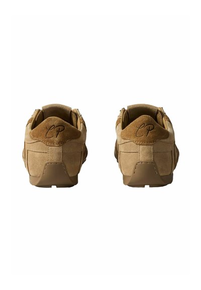 Paire de baskets en daim beige vues de dos, avec des semelles en caoutchouc marron et "CP" brodé sur les languettes de talon.