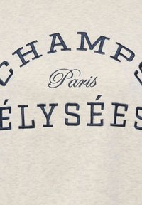 Beež kangas tikandiga mereväe tekstiga "CHAMPS ÉLYSÉES" kumera kujuga üleval ja sõna "Paris" kirjutatud käsikirjastiilis.