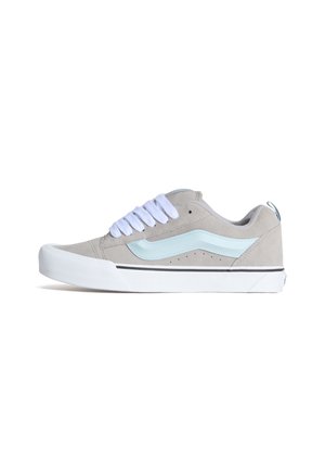 Szary zamszowy sneaker z jasnoniebieskimi akcentami, białymi sznurowadłami i czarnym paskiem wokół podeszwy środkowej. Zaokrąglony nosek i niski krój.