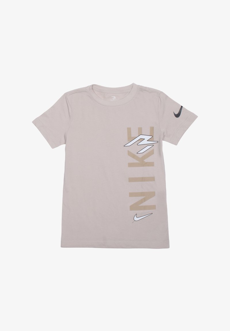 T-shirt beige à manches courtes de Nike avec un grand texte vertical "NIKE" et des logos swoosh sur la poitrine et la manche.