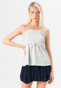 Lichtgrijze strapless top met smockdetails, verstelbare trekkoord in de taille, gecombineerd met een gelaagde marineblauwe rok.