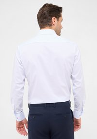 Weißes und hellblaues kariertes Hemd mit langen Ärmeln, Knopfmanschetten und taillierter Passform. Getragen mit navyfarbenen Hosen.