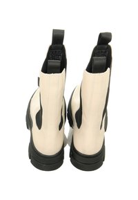 Weiße Leder-Stiefeletten mit schwarzen elastischen Seitenpanels, einer massiven schwarzen Sohle und Zugschlaufen an der Rückseite. Glatte Textur und minimalistisches Design.