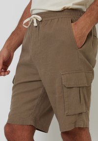 Lichte bruine cargoshorts van ademend materiaal, met een elastische tailleband en trekkoord, zijzakken en platte voorkeurszakken.