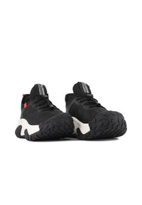 Baskets de sport noires avec une tige en tissu texturé, semelle intermédiaire blanche et semelle extérieure en caoutchouc noir robuste avec des motifs de crampons prononcés. Accent rouge sur le côté.