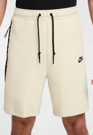 Shorts Nike color crema realizzati in tessuto morbido. Presentano un cordoncino nero, tasche laterali e un logo nero sulla gamba sinistra.