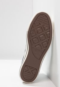 Hnědá guma podešve s texturovaným vzorem; má bílý okraj a branding po straně, umístěná na světlém pozadí.